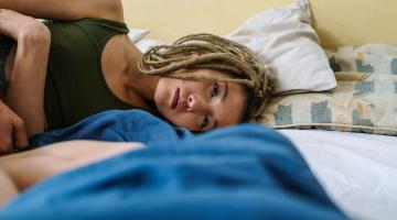 Zieke vrouw op bed vanwege post-COVID klachten